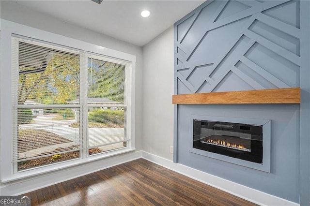 unfurnished living room featuring a large fireplace and dark hardwood / wood-style flooring