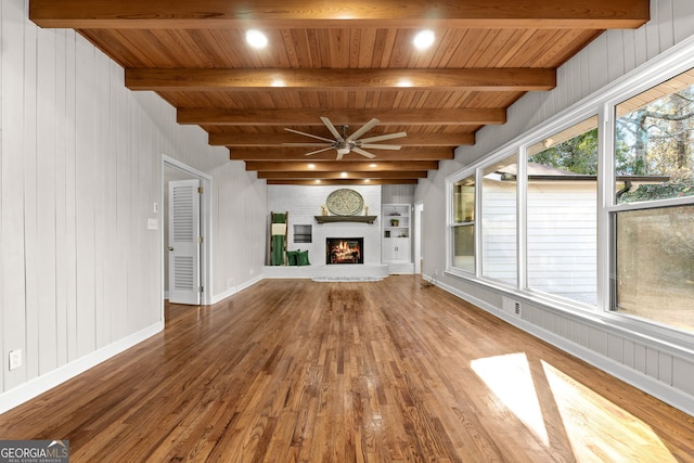 unfurnished living room featuring beamed ceiling, plenty of natural light, and wood ceiling