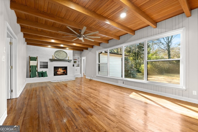 unfurnished living room with a brick fireplace, wood ceiling, ceiling fan, beam ceiling, and hardwood / wood-style flooring