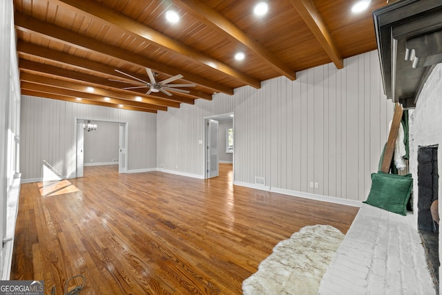 unfurnished living room featuring beamed ceiling, wood-type flooring, ceiling fan, and wood ceiling