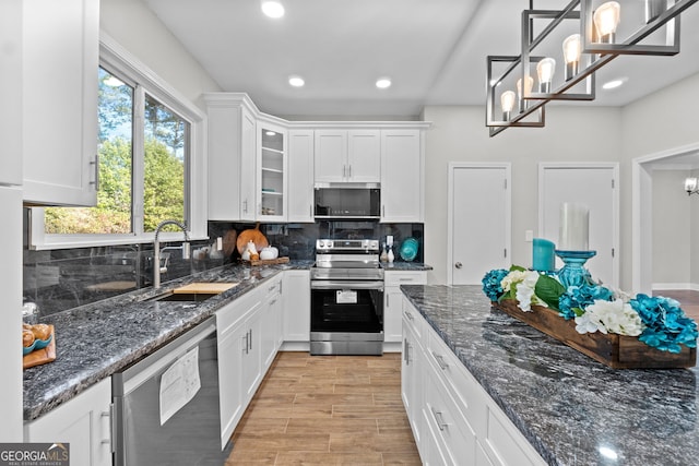 kitchen with appliances with stainless steel finishes, white cabinetry, and pendant lighting