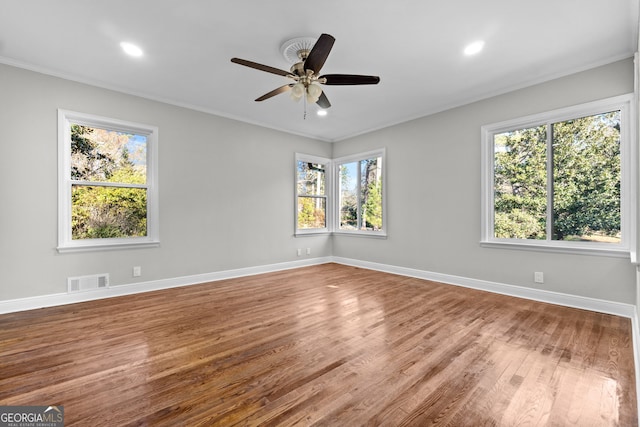 unfurnished room featuring a wealth of natural light, ceiling fan, ornamental molding, and hardwood / wood-style flooring