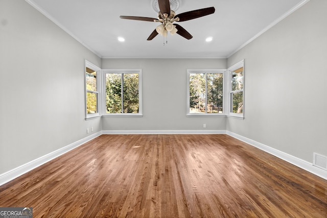 empty room featuring hardwood / wood-style flooring, plenty of natural light, ornamental molding, and ceiling fan