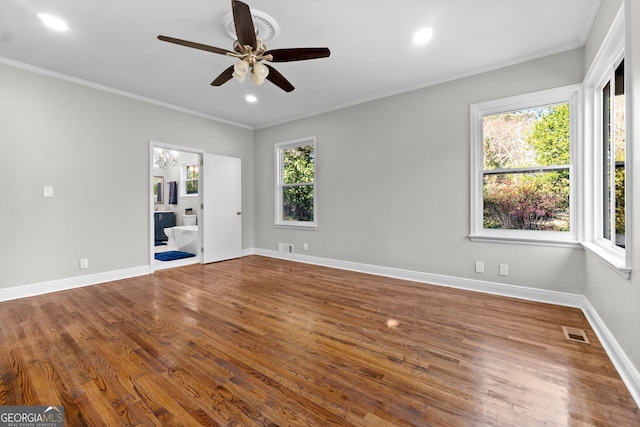 unfurnished room with a wealth of natural light, ceiling fan with notable chandelier, and hardwood / wood-style flooring