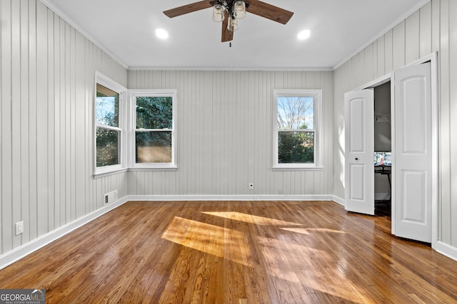 unfurnished bedroom with ceiling fan, a closet, wood-type flooring, and ornamental molding