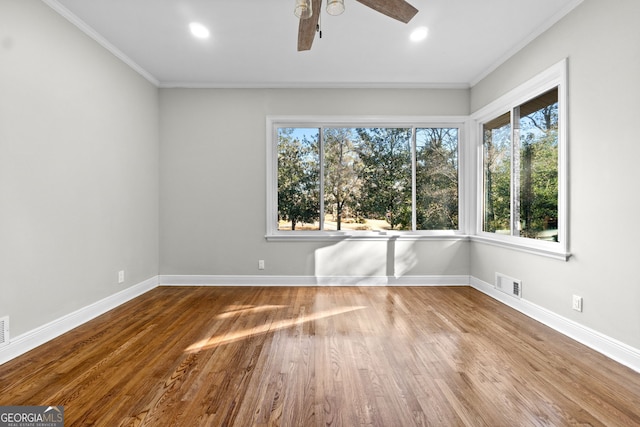 empty room featuring hardwood / wood-style floors, ceiling fan, a healthy amount of sunlight, and crown molding