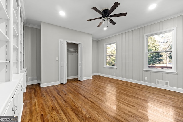 unfurnished bedroom featuring ceiling fan, a closet, crown molding, and hardwood / wood-style flooring