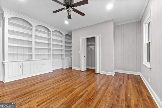 interior space featuring ceiling fan, wood-type flooring, and crown molding