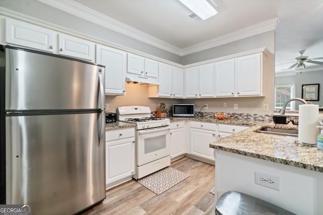 kitchen featuring stainless steel fridge, white gas range, ceiling fan, sink, and white cabinets