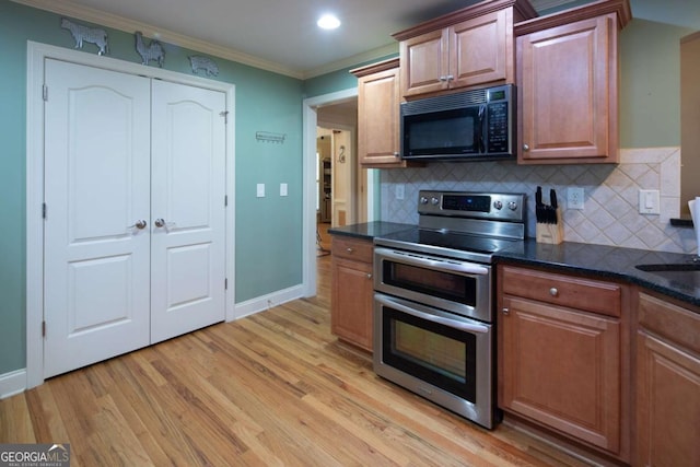 kitchen featuring tasteful backsplash, crown molding, double oven range, and light hardwood / wood-style floors