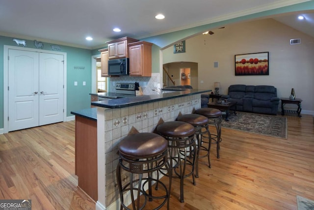 kitchen with kitchen peninsula, electric stove, crown molding, and a breakfast bar