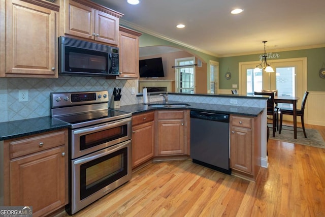 kitchen with pendant lighting, sink, light hardwood / wood-style flooring, appliances with stainless steel finishes, and kitchen peninsula