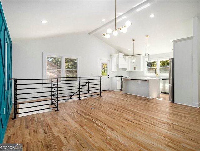 kitchen with appliances with stainless steel finishes, a kitchen island, decorative light fixtures, white cabinetry, and custom exhaust hood