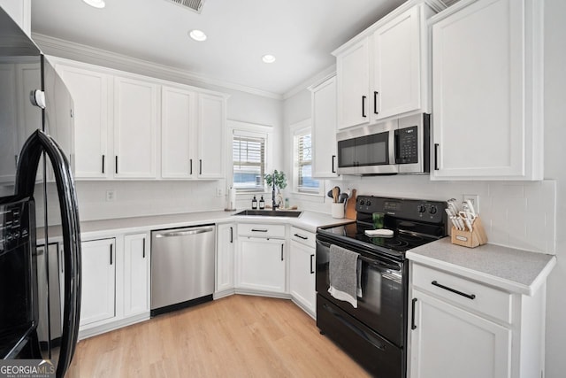 kitchen with backsplash, light hardwood / wood-style flooring, white cabinets, and appliances with stainless steel finishes