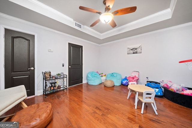 rec room featuring a tray ceiling, ceiling fan, hardwood / wood-style floors, and ornamental molding