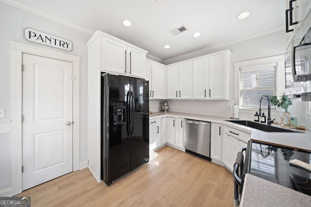 kitchen with stainless steel dishwasher, black fridge, white cabinetry, and sink