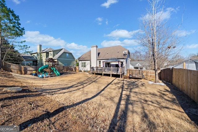 back of house featuring a playground and a wooden deck