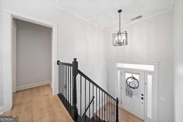 foyer featuring light hardwood / wood-style flooring, a chandelier, and ornamental molding