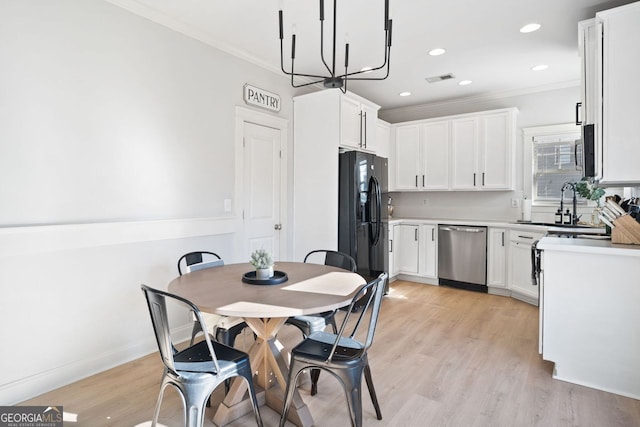 kitchen with white cabinets, crown molding, stainless steel appliances, and light hardwood / wood-style flooring