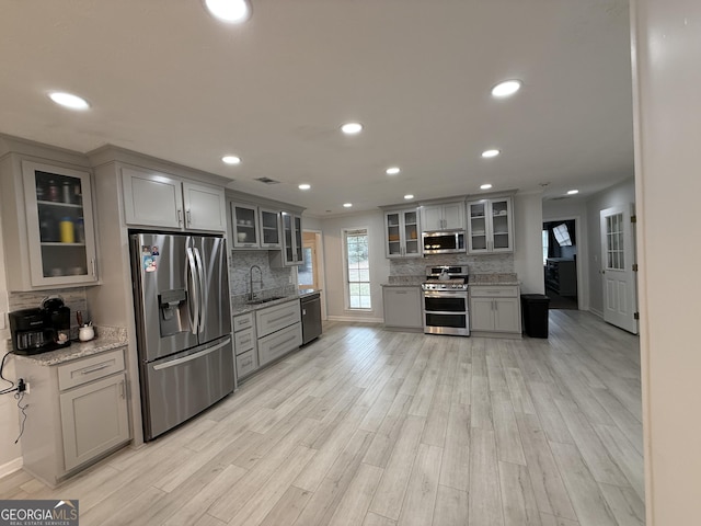 kitchen with gray cabinets, light stone countertops, and stainless steel appliances