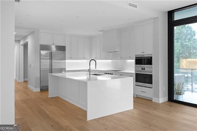 kitchen with white cabinetry, sink, an island with sink, and stainless steel appliances