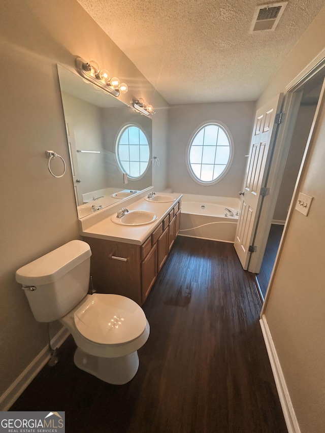 bathroom with vanity, a textured ceiling, hardwood / wood-style flooring, and a bathing tub