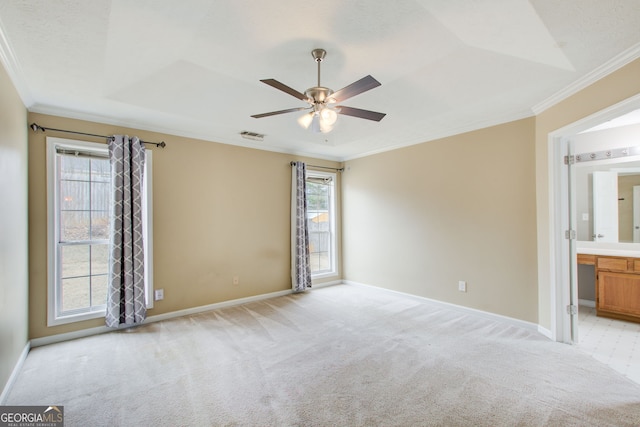 unfurnished bedroom with ceiling fan, crown molding, multiple windows, and ensuite bath