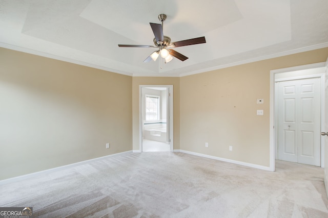 carpeted empty room featuring ceiling fan, a tray ceiling, and ornamental molding