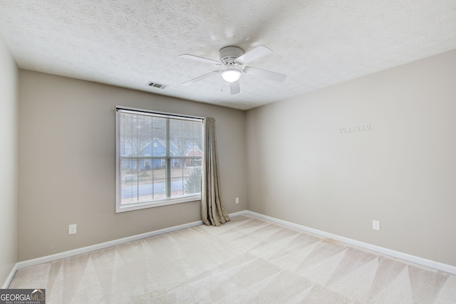 unfurnished room with ceiling fan, light colored carpet, and a textured ceiling