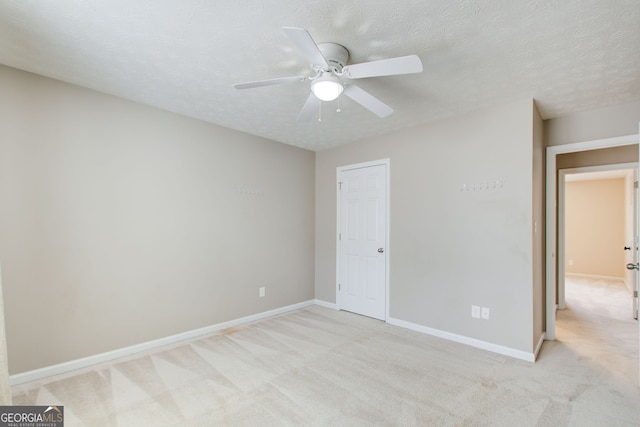 unfurnished bedroom with ceiling fan, a textured ceiling, and light carpet