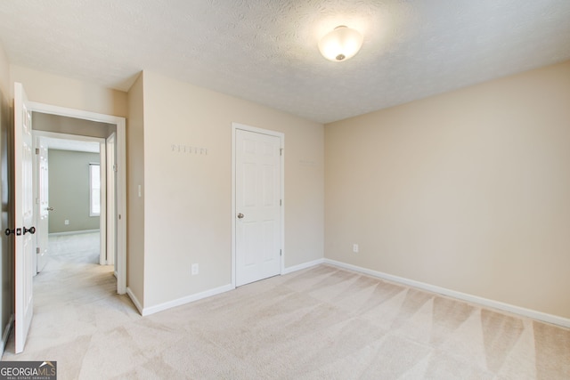 interior space with a closet, a textured ceiling, and light carpet