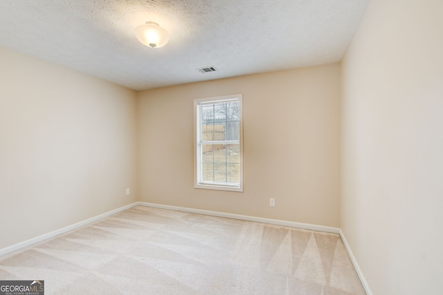 spare room featuring a textured ceiling and light colored carpet