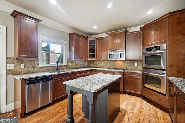 kitchen featuring light stone counters, sink, ornamental molding, and appliances with stainless steel finishes