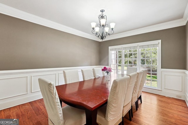 dining space featuring wood-type flooring, crown molding, and a chandelier