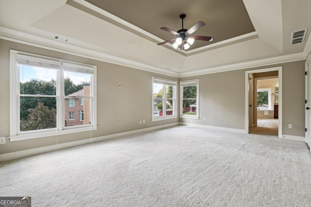 empty room featuring a tray ceiling, crown molding, ceiling fan, and light colored carpet