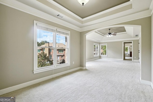 unfurnished room featuring a raised ceiling, ceiling fan, crown molding, and carpet floors