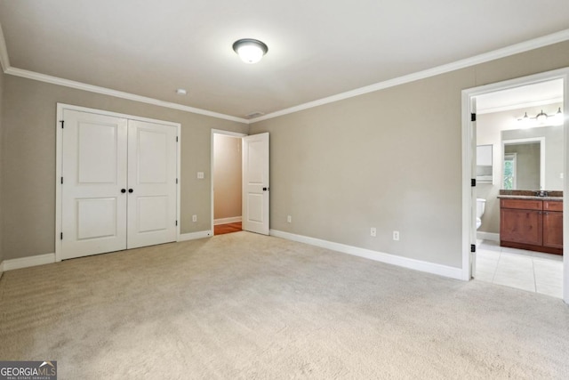 unfurnished bedroom with connected bathroom, a closet, light colored carpet, and ornamental molding