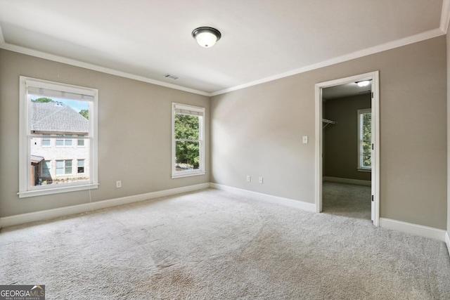 carpeted spare room featuring plenty of natural light and crown molding