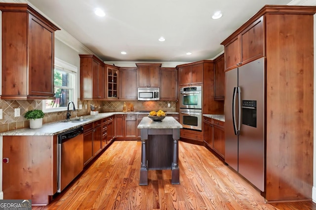 kitchen with a center island, backsplash, sink, appliances with stainless steel finishes, and light hardwood / wood-style floors