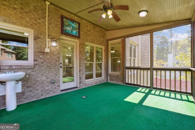 unfurnished sunroom featuring ceiling fan, sink, wood ceiling, and lofted ceiling