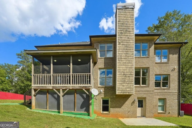 rear view of house featuring a yard and a sunroom