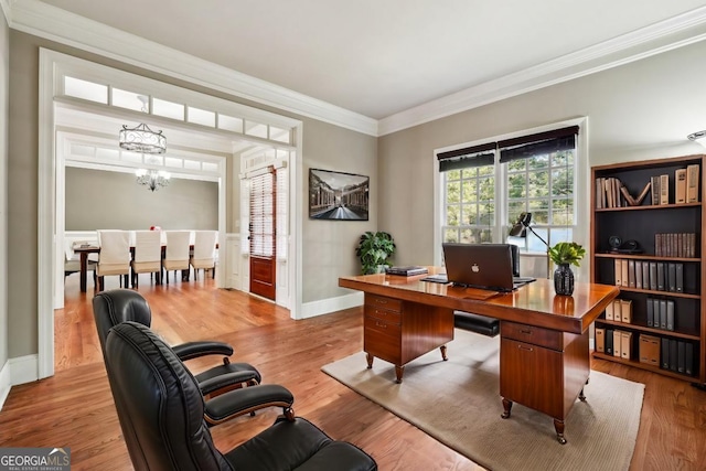 office with light hardwood / wood-style floors, ornamental molding, and an inviting chandelier