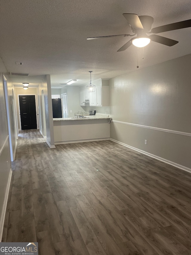 unfurnished living room with a textured ceiling, ceiling fan, and dark wood-type flooring