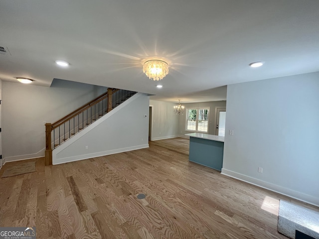 unfurnished living room featuring light hardwood / wood-style floors and an inviting chandelier