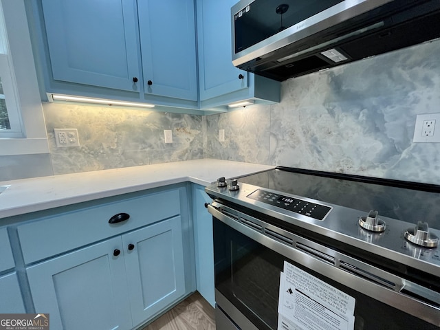 kitchen featuring decorative backsplash, blue cabinets, and stainless steel range with electric cooktop