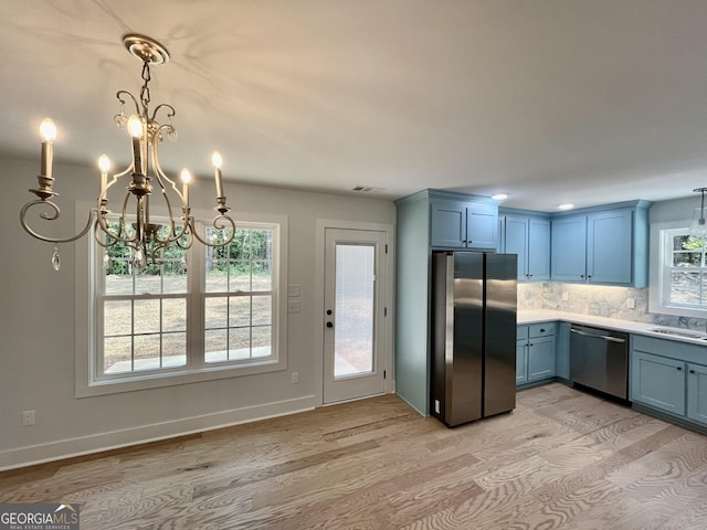 kitchen with tasteful backsplash, hanging light fixtures, stainless steel appliances, and a notable chandelier