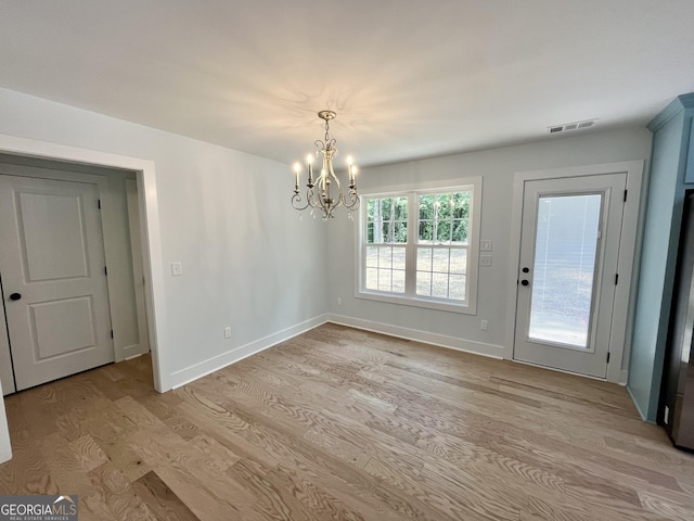 unfurnished dining area featuring light wood-type flooring and a notable chandelier