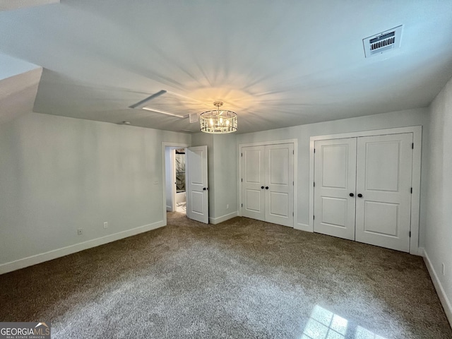 unfurnished bedroom featuring carpet, two closets, and an inviting chandelier