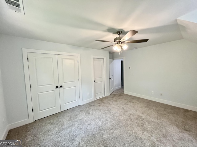 unfurnished bedroom featuring ceiling fan, carpet floors, and multiple closets