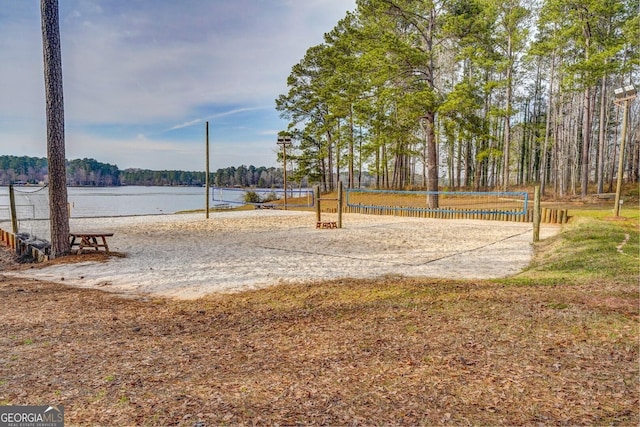 surrounding community with a water view and volleyball court